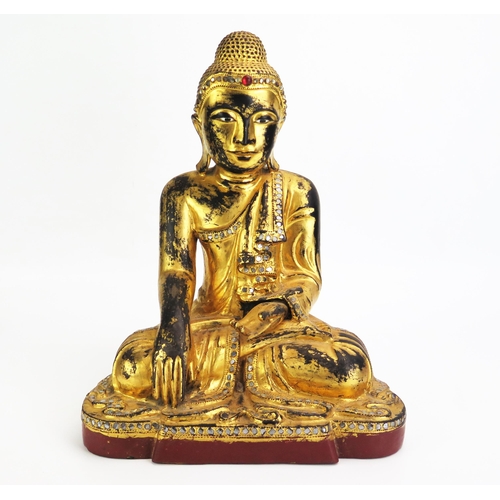 1155 - A carved hardwood, gilded and paste set model of Buddha, seated cross-legged wearing traditional rob... 