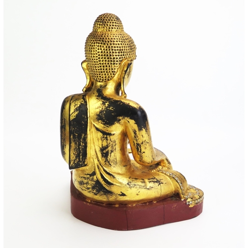 1155 - A carved hardwood, gilded and paste set model of Buddha, seated cross-legged wearing traditional rob... 