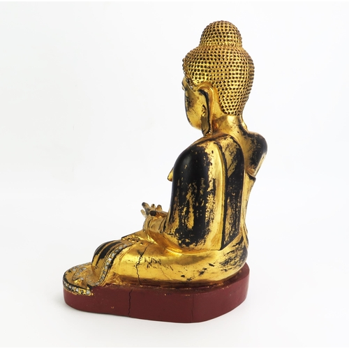 1155 - A carved hardwood, gilded and paste set model of Buddha, seated cross-legged wearing traditional rob... 