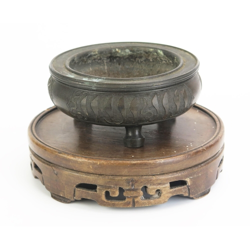 1169 - A Chinese bronze circular censer, of squat circular form with script to the sides, raised on three p... 