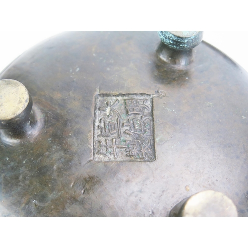 1169 - A Chinese bronze circular censer, of squat circular form with script to the sides, raised on three p... 