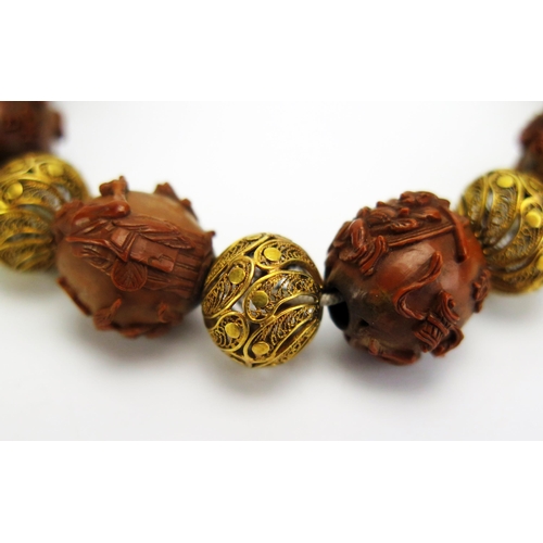 1192 - A Chinese carved nut and yellow metal filigree bracelet, each bead decorated with either figures or ... 