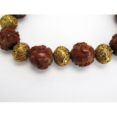 1192 - A Chinese carved nut and yellow metal filigree bracelet, each bead decorated with either figures or ... 