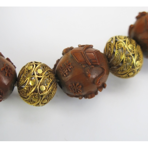 1192 - A Chinese carved nut and yellow metal filigree bracelet, each bead decorated with either figures or ... 