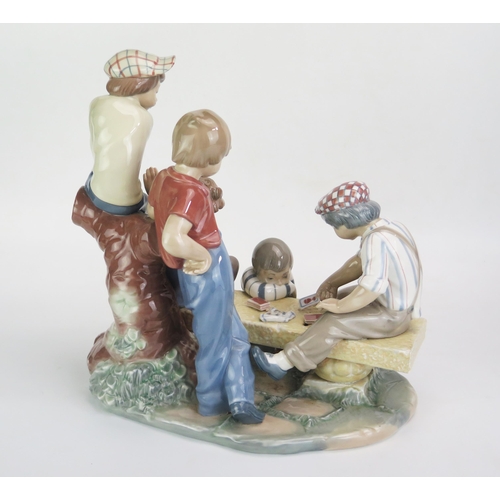 1045 - A large Nao porcelain figure group of street urchins playing cards on a bench, 32cm high, 30cm wide.