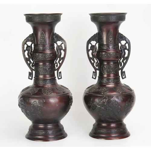 1081 - A pair of Japanese bronze vases of archaic design with flared rims, slender neck and ovoid body on a... 