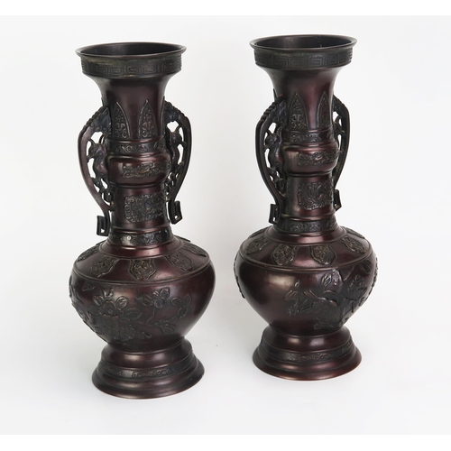 1081 - A pair of Japanese bronze vases of archaic design with flared rims, slender neck and ovoid body on a... 