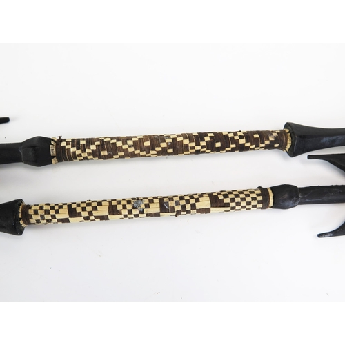 Two tribal carved wood fishing spears, with serrated blades and woven  raffia handles, 64cm long