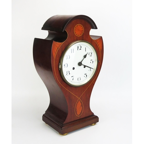 1113A - An Edwardian mahogany and inlaid mantel clock, of broken balloon shaped outline, inlaid with fan and... 