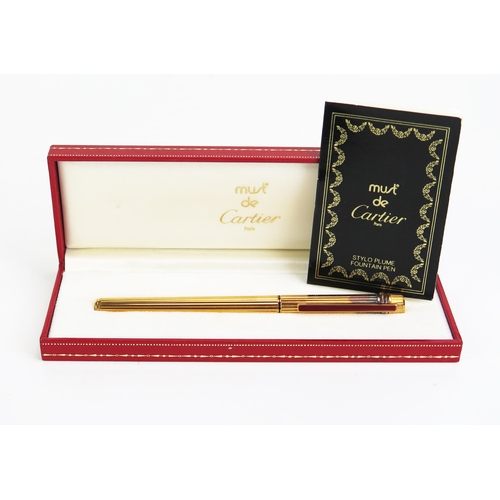 1123 - Must de Cartier, Paris, a gilt metal fountain pen with 18K gold nib, serial No 100216, with case and... 