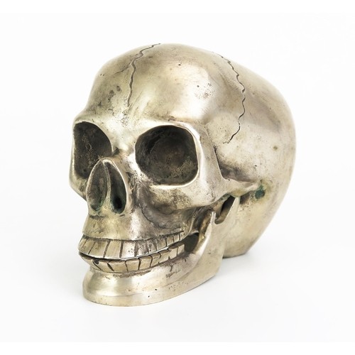 1126 - A metal paperweight in the form of a skull with hinged jaw, 12cm long.