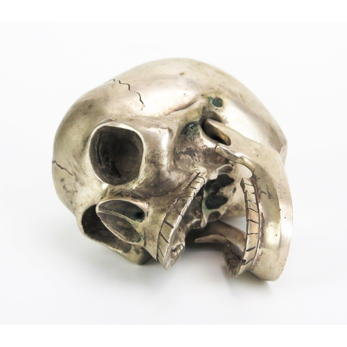 1126 - A metal paperweight in the form of a skull with hinged jaw, 12cm long.