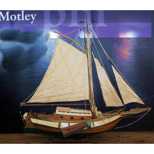 1339 - A model of a single masted yacht, the half painted hull of clinker construction, cabin, main sail an... 