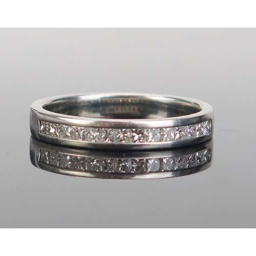 142 - A Platinum and Diamond Half Eternity Ring, with fourteen c. 2.4mm channel set princess cut stones, s... 