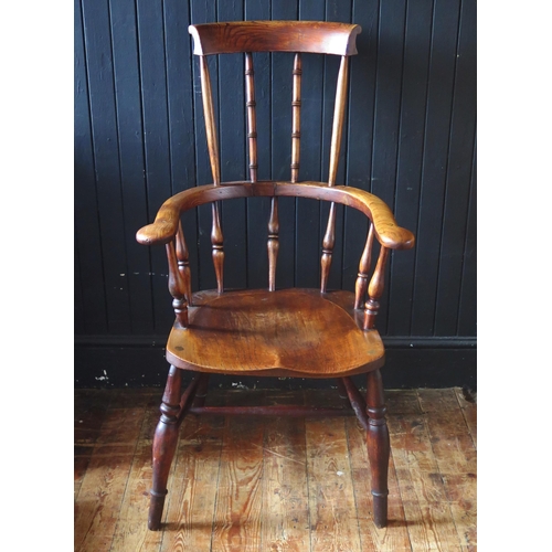 1421 - A late Georgian elm Windsor style elbow chair, with high comb back, solid seat on turned legs united... 