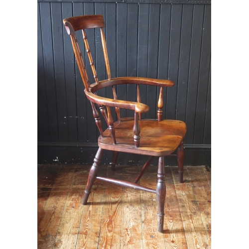 1421 - A late Georgian elm Windsor style elbow chair, with high comb back, solid seat on turned legs united... 