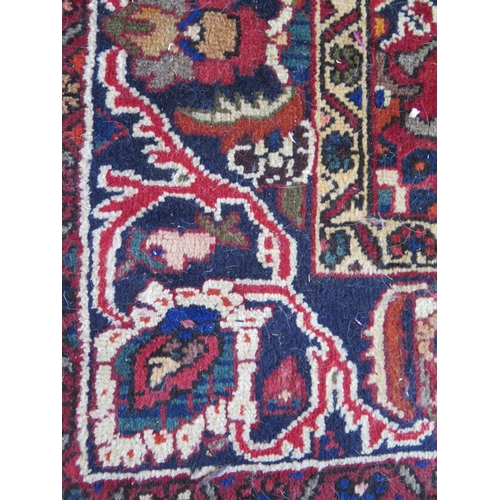 1433 - A Bakhtiari rug, the wine red field with four rows of flowerhead medallions, enclosed by a triple fl... 