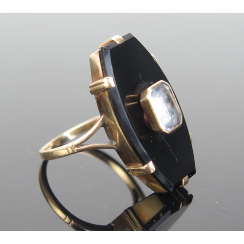 200 - A Gent's Coffin Shaped Ring mounted with a black onyx or glass panel and a foil backed pale blue eme... 