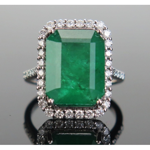 A Modern 18K White Gold, Emerald and Diamond Ring, the central 10.53ct 14x11x6.7mm stone with c. 1.8mm brilliant round cuts, stamped 18K, size M.5, 6.5g. Presented in a W. Bruford box
