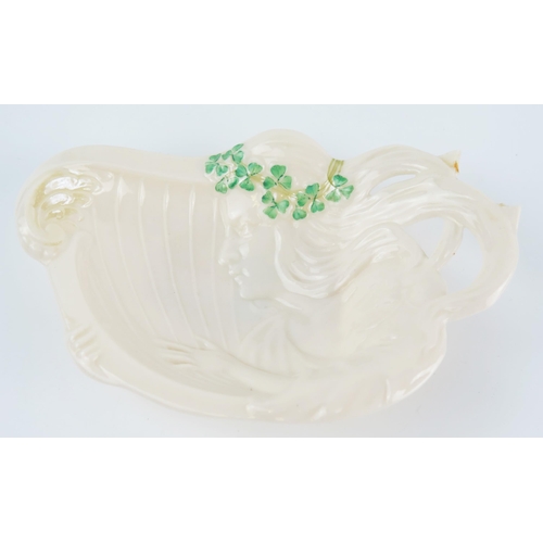 1039 - A Belleek porcelain heart-shaped dish, two egg cups and an Art Nouveau influence dish of a maid play... 