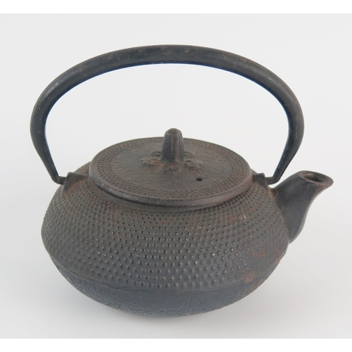 1119 - A Japanese iron kettle, of squat circular form with loop swing handle, 15cm long.