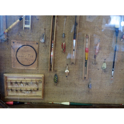 1223 - A collection of fishing floats, trout flies, and lures mounted in a glazed display case. 90 x 90cm.