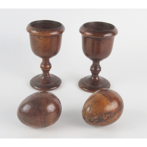 1238 - A pair of 189th century treen egg cups, together with treen eggs, 13cm high.