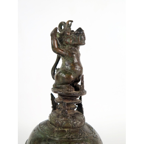 1352 - An Indonesian bronze temple bell, of globular outline, the handle in the form of a Makara, 25cm high... 