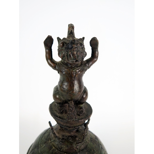 1352 - An Indonesian bronze temple bell, of globular outline, the handle in the form of a Makara, 25cm high... 