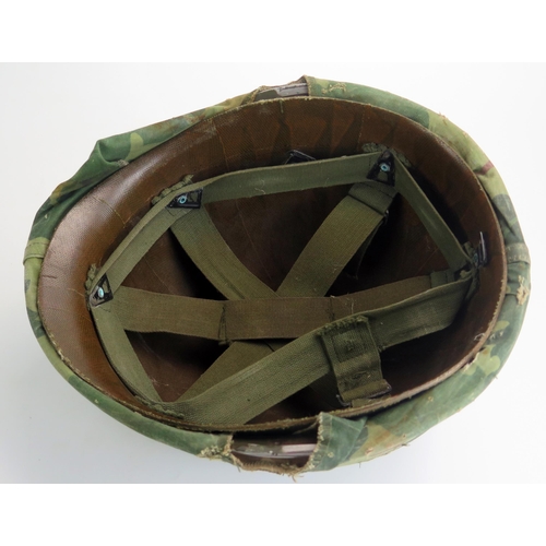 1385 - An American M1 pattern helmet with liner and camouflage cover, possibly Vietnam period.