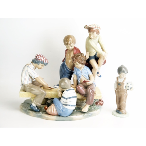 1504 - A large Nao porcelain figure group of street urchins playing cards on a bench, 32cm wide, 33cm high.... 