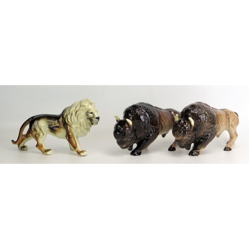 1512 - A pair of Melba Ware Buffalo, each 26cm long, together with a pottery figure of a lion, 26cm long.(3... 