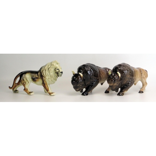 1512 - A pair of Melba Ware Buffalo, each 26cm long, together with a pottery figure of a lion, 26cm long.(3... 