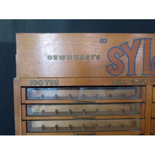 1627 - A Dewhurst's machine twist SYLKO haberdashery cabinet, with glazed front sliding drawers for cotton ... 