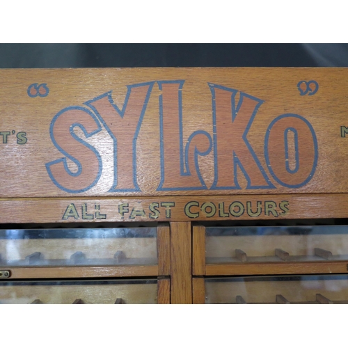 1627 - A Dewhurst's machine twist SYLKO haberdashery cabinet, with glazed front sliding drawers for cotton ... 