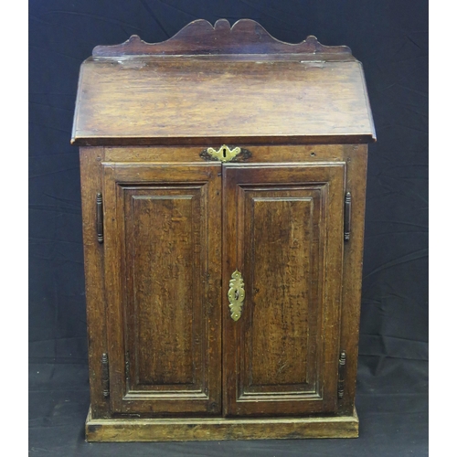 1644 - An antique oak bureau,  with sloping hinged fall,  and a pair of panelled cupboard doors below, on a... 