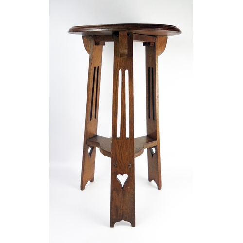 1653 - An Edwardian oak jardinière stand, the circular top with a moulded edge, raised on three pierced sup... 