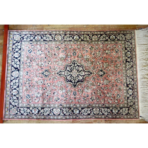 1661 - A Persian rug, the main salmon pink field with indigo pole medallion within trailing flowers and fol... 