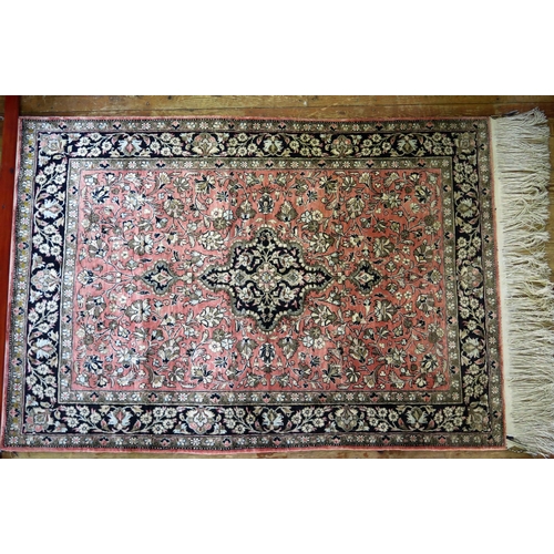 1661 - A Persian rug, the main salmon pink field with indigo pole medallion within trailing flowers and fol... 