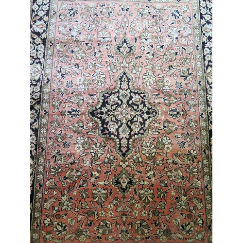 1661 - A Persian rug, the main salmon pink field with indigo pole medallion within trailing flowers and fol... 