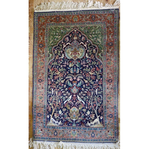 1662 - A Persian silk and wool prayer rug, the indigo mihrab with a garden design of animals and birds amon... 