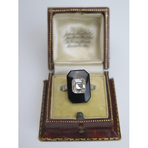 254 - An Emerald Cut Diamond and Onyx Ring in a platinum setting with three baguette cut diamonds to each ... 