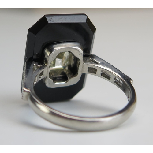 254 - An Emerald Cut Diamond and Onyx Ring in a platinum setting with three baguette cut diamonds to each ... 