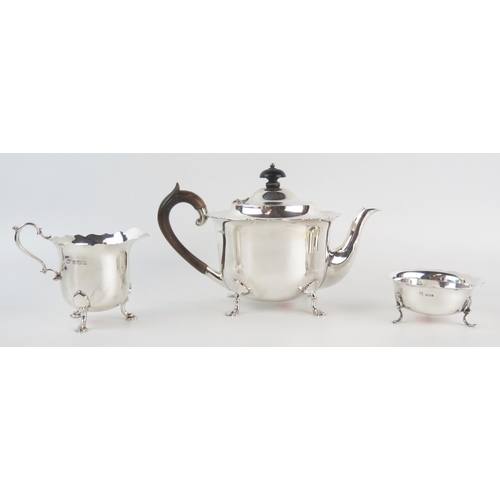 595 - A matched silver three-piece tea set, various makers and dates, of cylindrical form with wavy-edge b... 