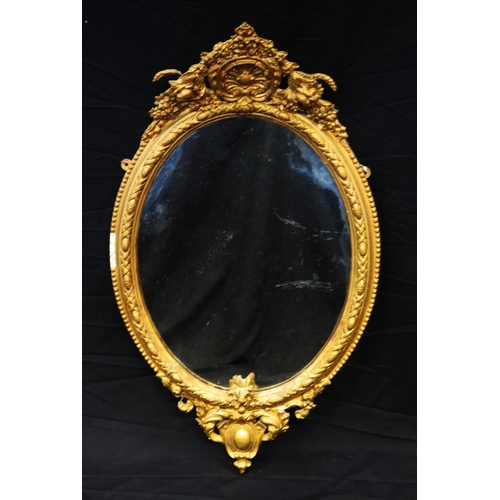 1677 - A Gilt wall mirror with oval mirror plate enclosed by a floral decorated frame surmounted by floral ... 