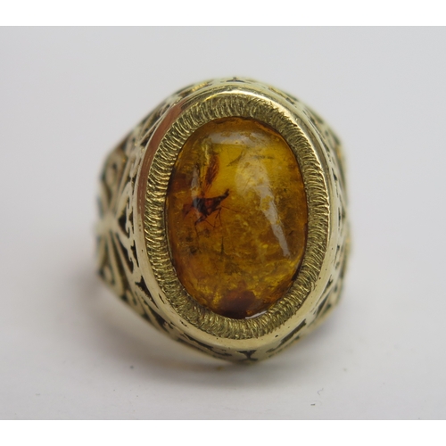 124 - An 18ct Gold and Amber Ring with insect inclusion and pierced foliate shoulders, stamped 18, size I,... 