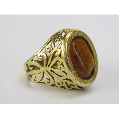 124 - An 18ct Gold and Amber Ring with insect inclusion and pierced foliate shoulders, stamped 18, size I,... 