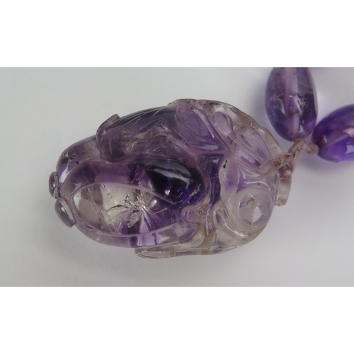 21 - A Chinese Caved Amethyst Pendant (44.8mm drop) and on an oval bead necklace, c. 29