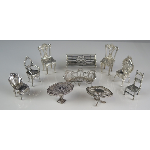 544 - A collection of silver miniature furniture including garden bench, two filigree tables, filigree set... 