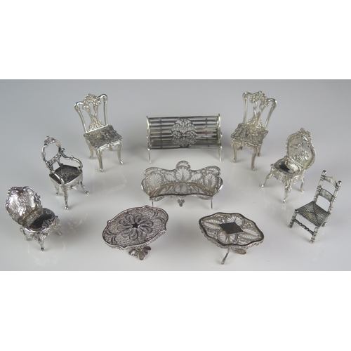 544 - A collection of silver miniature furniture including garden bench, two filigree tables, filigree set... 